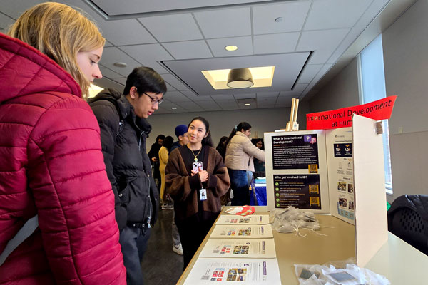 Three people around International Development info table