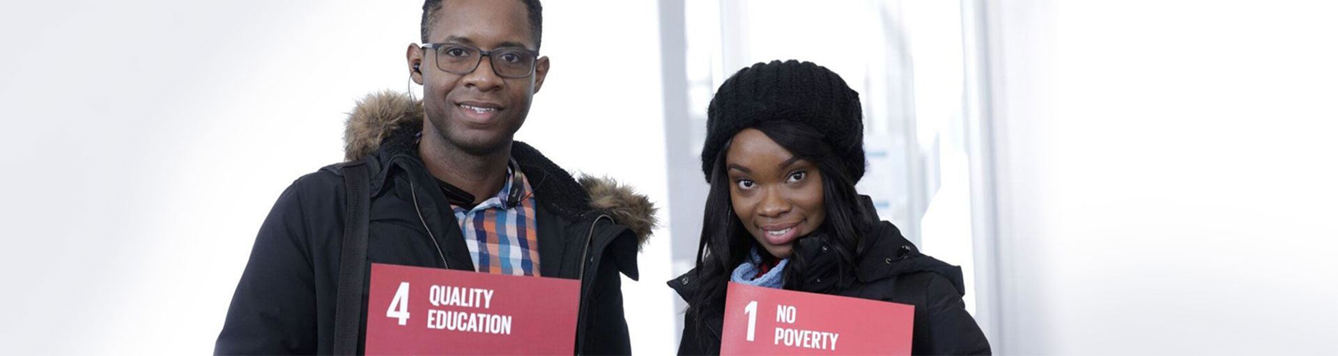 man and woman holding signs and smiling