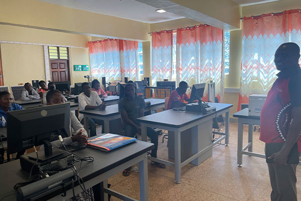 a group of people sitting at tables in a room with computers